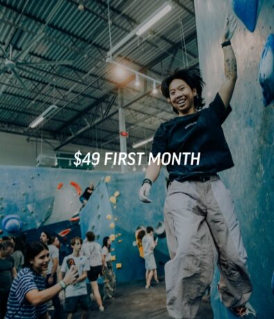 A smiling person climbing a blue indoor rock wall with the text $49 FIRST MONTH overlaid.