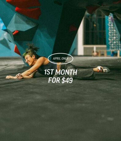 A woman smiling while lying on the floor of an indoor climbing gym. Text overlay reads: APRIL ONLY 1ST MONTH FOR $49.