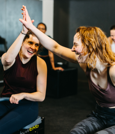 Two women high five after a workout