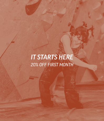 A person in climbing gear smiles while standing in front of the Bouldering Project Minneapolis Indoor Climbing Gym. Text overlay reads: IT STARTS HERE. 20% OFF FIRST MONTH.
