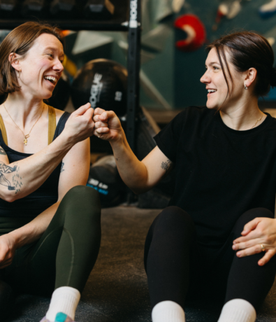 Two women fist bump during a strength class at Bouldering Project