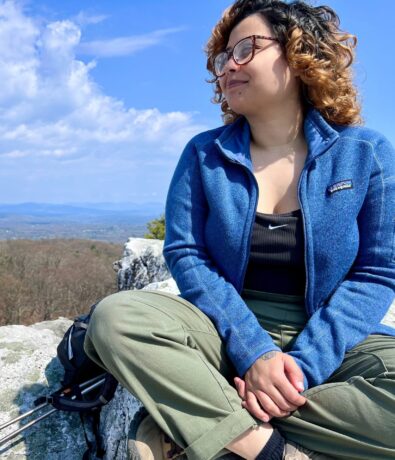 photo of rosie sitting on a rock overlooking a wooded valley