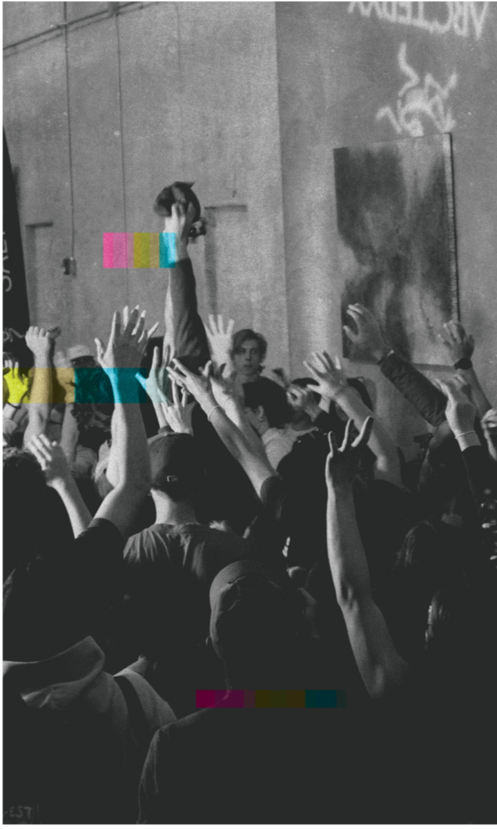 A black-and-white photo of a crowd at Boulderfest 2025, with many people raising their hands. Colored rectangles overlay parts of the image, and graffiti is visible on the wall in the background.