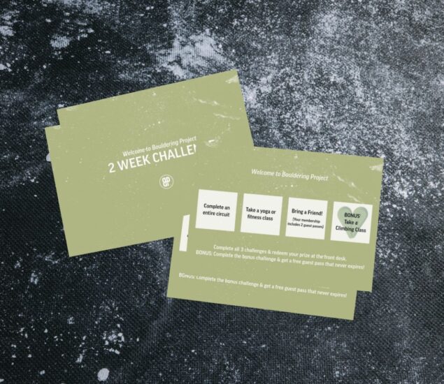 Two green cards on a dark, textured surface, promoting a 2-week bouldering challenge with tasks like circuit completion and bringing a friend. Text details rewards such as a guest pass and discounted membership for successful participants.