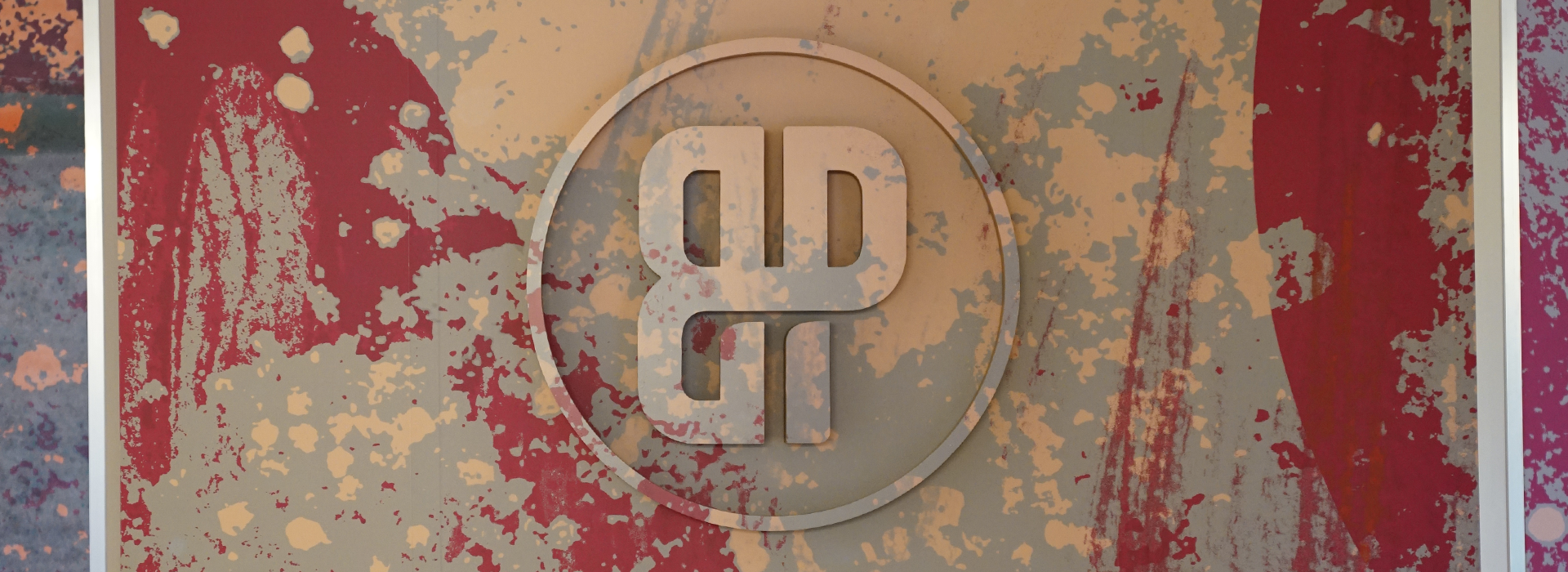 A stylized BR logo inside a circle is centered on a textured background of red, tan, and beige paint splatters, evoking an abstract, artistic vibe inspired by the dynamic energy of a St Paul rock climbing gym.