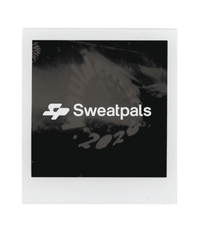 A black and white Polaroid photo with the word Sweatpals and a stylized logo in the center, partially obscuring faint, handwritten text and numbers in the background, celebrates Boulderfest 2026.