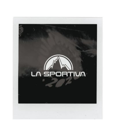 A Polaroid photo featuring the La Sportiva logo with a stylized mountain graphic on a dark background, captured at Boulderfest 2026. Subtle white markings and shapes are faintly visible behind the logo.