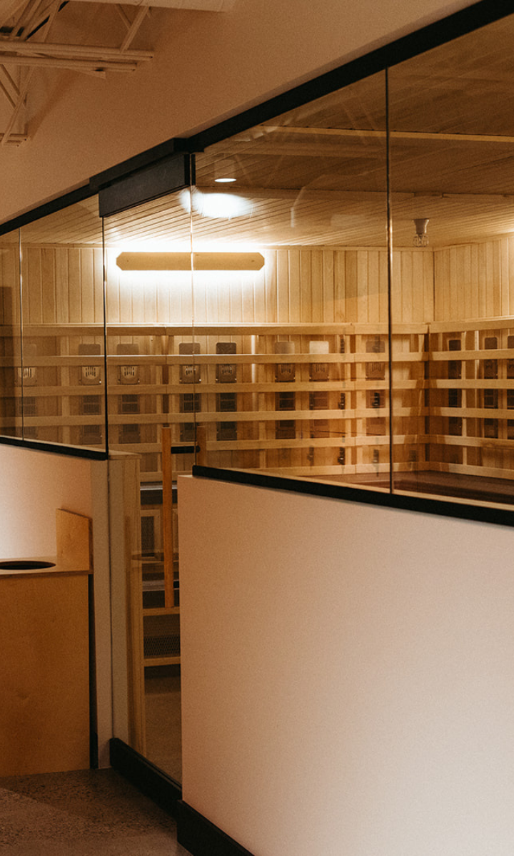A modern, minimalistic room with wooden walls and shelving, seen through a glass partition. Warm lighting creates a cozy atmosphere—perfect for unwinding after a day of climbing Seattle—with a light-colored desk or counter in the foreground.