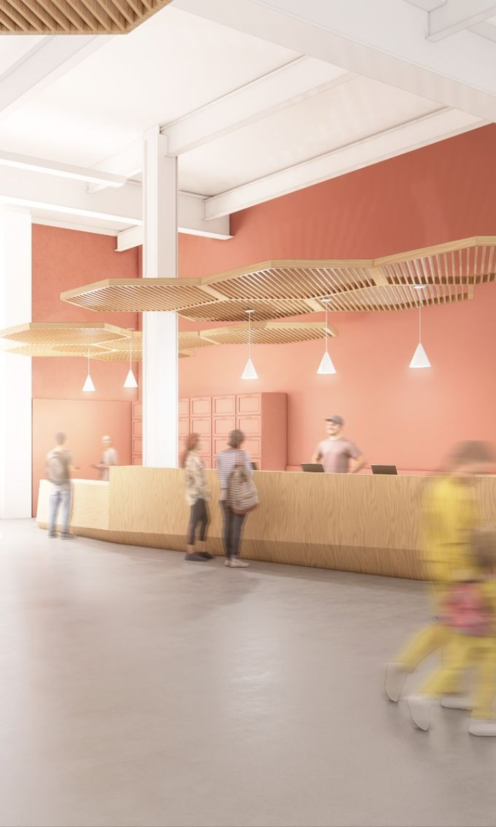 A modern lobby with a wooden reception desk, unique overhead wooden decor, pendant lights, and several blurred people walking or standing in front of the desk sets the welcoming tone for this dc climbing gym. The walls are a soft reddish hue, creating an inviting atmosphere for climbers and visitors alike.
