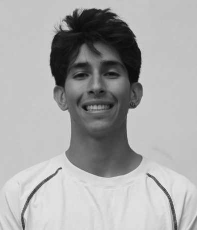 A smiling young man in a t-shirt poses for a portrait against a plain background during the Boulderfest community climbing competition.