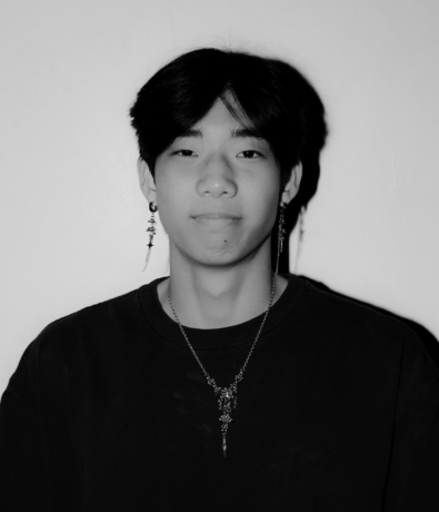 A black and white portrait of a young person wearing long dangling earrings and a pendant necklace, captured at the Bouldering Project Boulderfest community climbing competition.