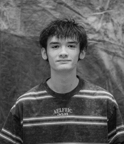 A young person with messy hair wearing an Aelfric Eden striped shirt at the Bouldering Project boulderfest community climbing competition.