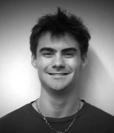 Black and white portrait of a smiling young man wearing a chain necklace at the Boulderfest climbing competition.