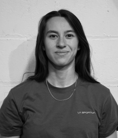 A young woman with long hair wearing a La Sportiva t-shirt at a bouldering project climbing competition.