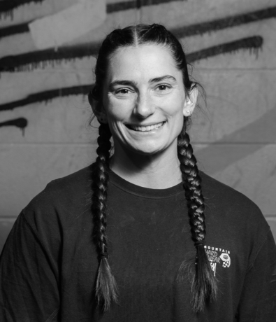 A smiling woman with braided hair wearing a Mountain Hardwear t-shirt at the Bouldering Project.