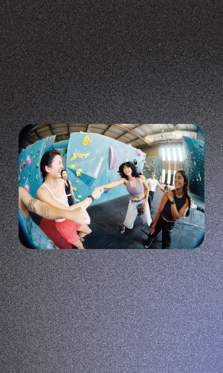 Four people smiling and high-fiving at an indoor rock climbing gym, captured for a marketing strategy brand campaign.