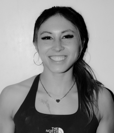 A smiling woman wearing a black athletic top with The North Face logo at a Bouldering Project climbing competition.