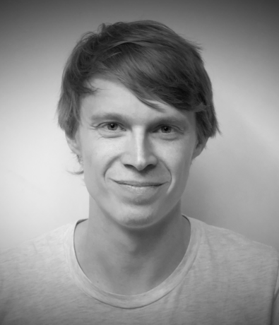 Black and white headshot of a smiling young man in a t-shirt at the Bouldering Project.