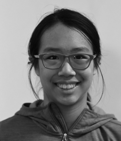 A smiling young person in glasses and a hooded jacket at the Bouldering Project.
